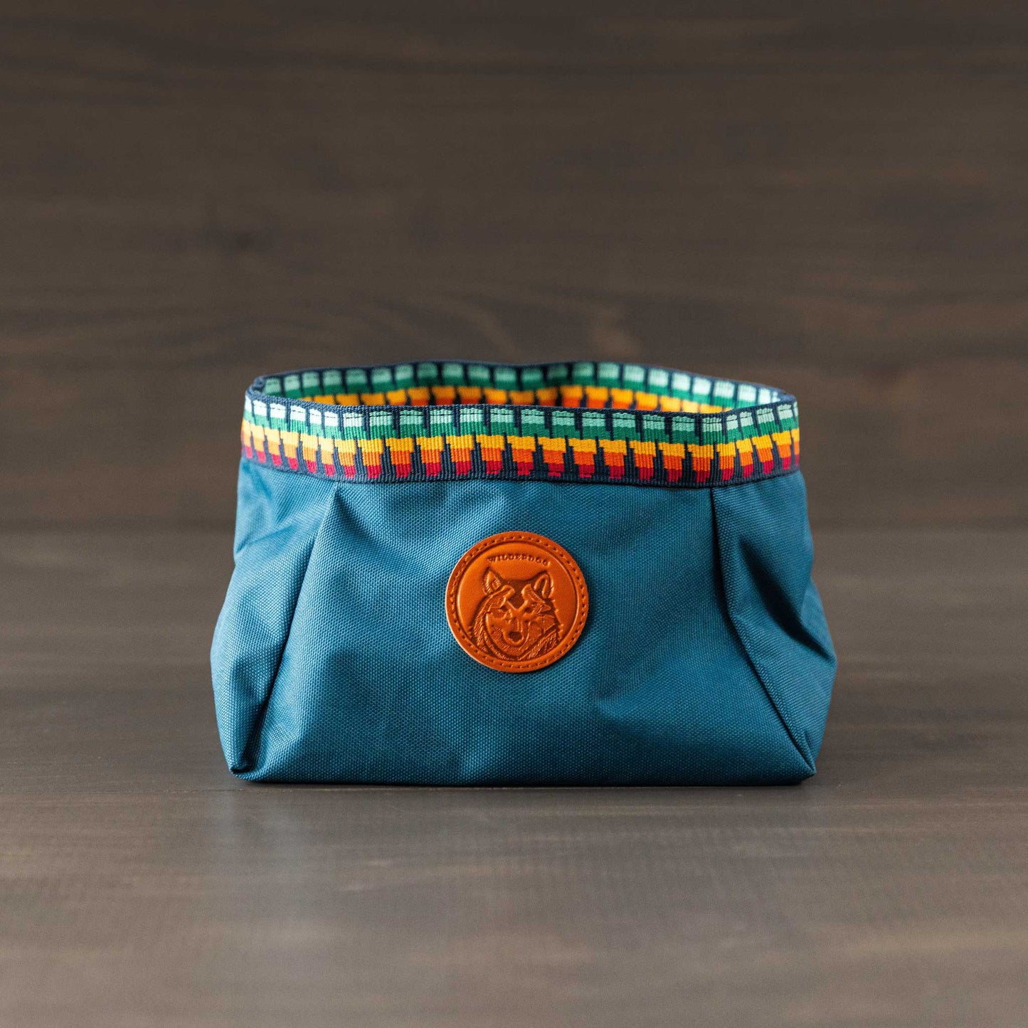 A versatile blue Backpacking Bowl with a patterned rim and brown leather owl patch, made from heavy-duty water-resistant fabric. Ideal for indoor or outdoor use, it's set against a neutral background.