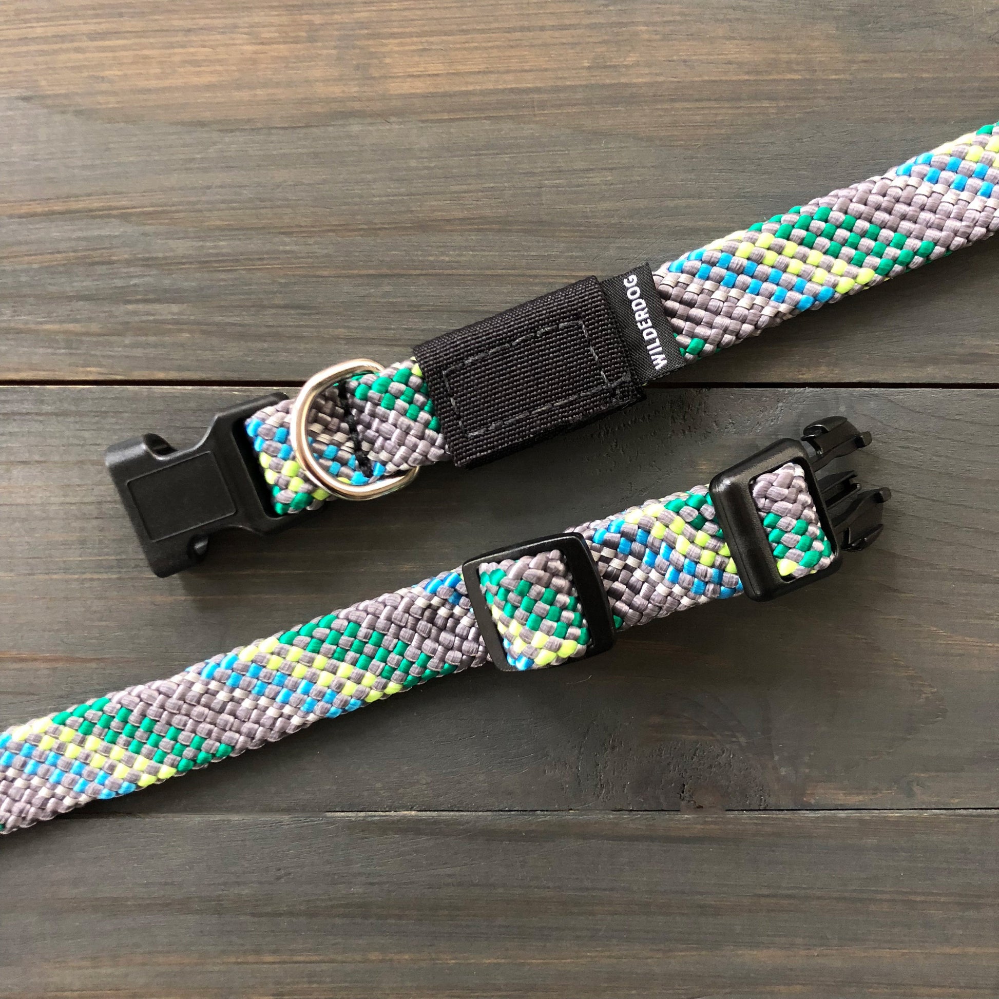 The Alpine Reflective Collar and matching leash set, crafted with the durability of rock climbing rope, displayed on a wooden surface. Featuring a blend of gray, blue, green, and yellow patterns, it includes black plastic clips and a silver D-ring for tags or leash attachment.