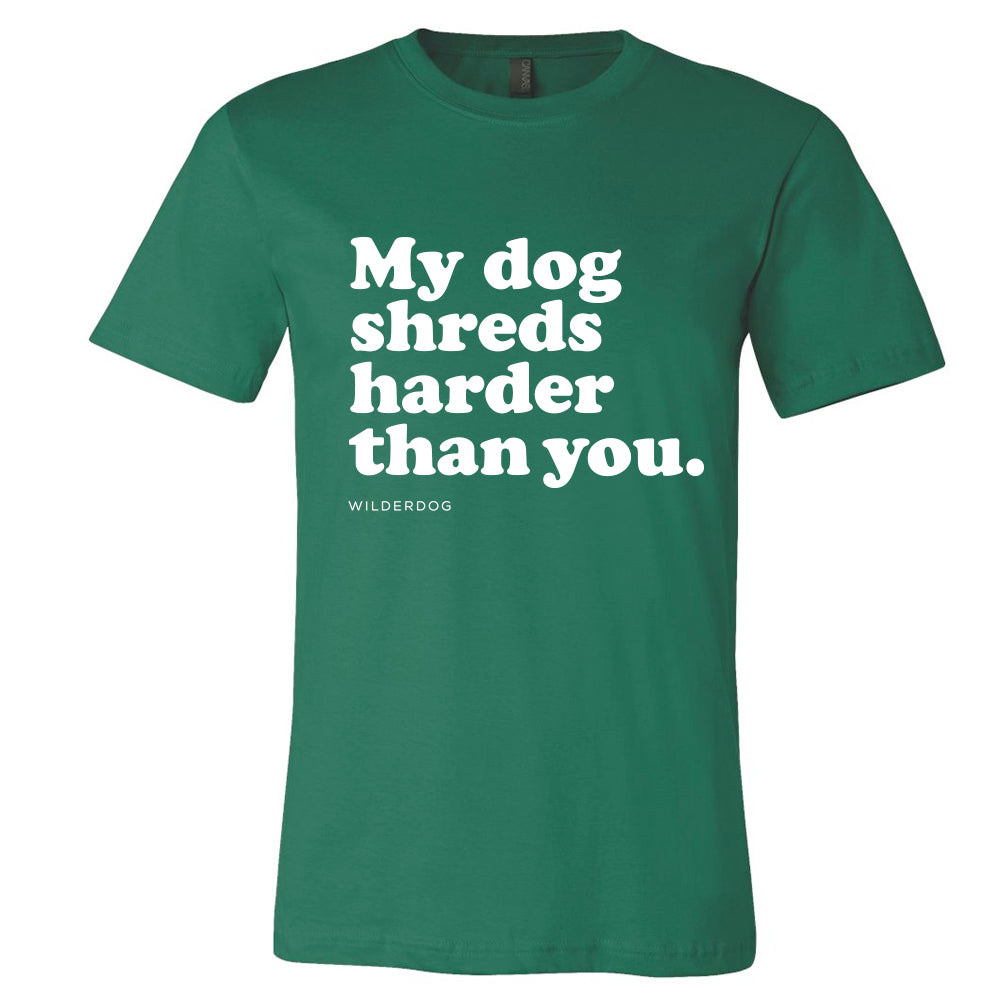 Introducing the Party Dog Tee Shirt: This vibrant green, sustainably produced unisex t-shirt features white text that reads "My dog shreds harder than you," centered on the chest. Below in smaller letters, you'll find the brand name "Wilderdog," making this shirt a fusion of style and eco-friendliness.